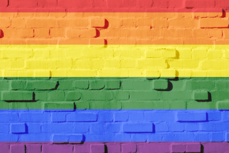 [ai] A brick wall painted with horizontal stripes in the colors of the rainbow: red, orange, yellow, green, blue, and purple.